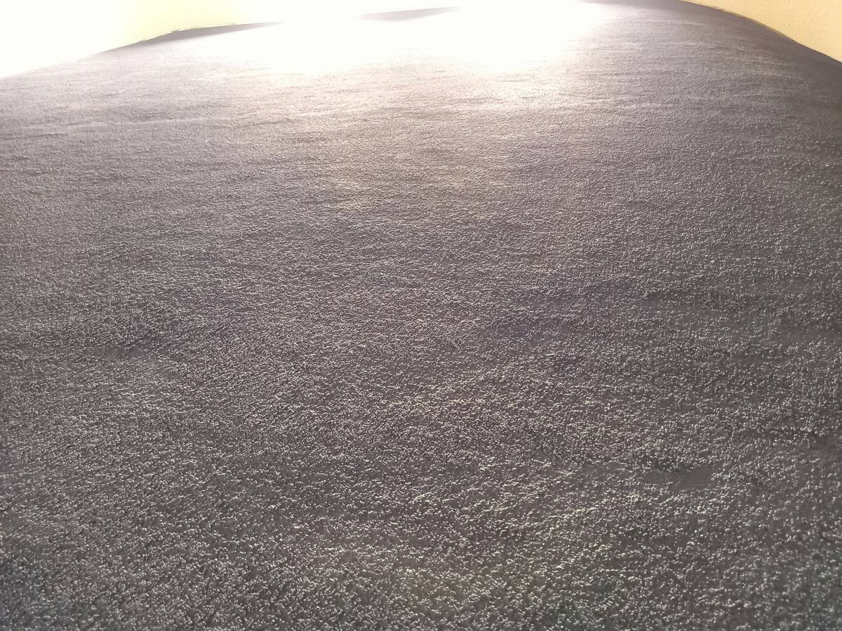 Close-up of vapor barrier installation under carpet padding on concrete floor